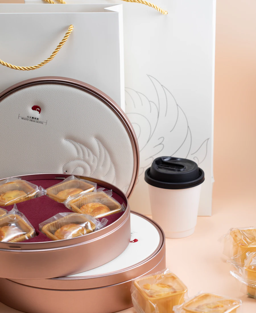 A round printed gift tin with pastries beside matching packaging